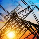 The sun sets behind a power source